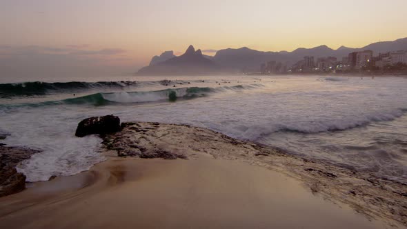 Static shot of surfers, people wading in water and waves.