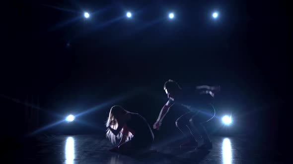 Young Couple Dancing Contemp Against Black Background with Spotlights at Studio.