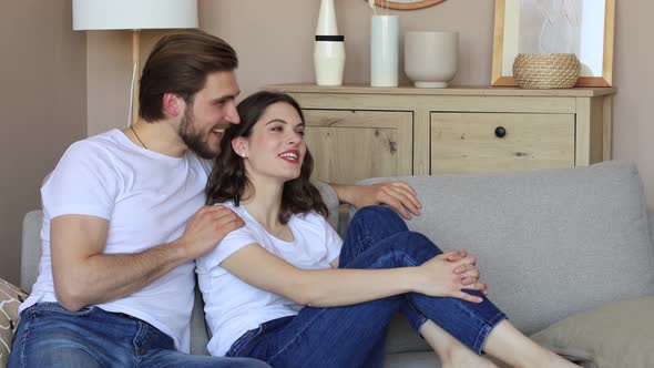 Young loving couple relaxing on sofa together. Woman and man embrace enjoy company of each other
