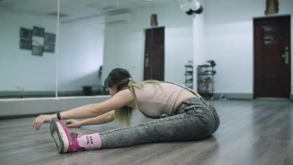 Caucasian female dancer choreographer stretching and warming up on the floor of a dance studio