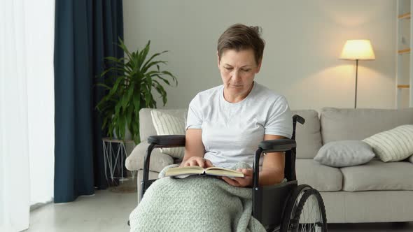 Senior Woman Sitting on the Wheelchair Reading a Book at Home