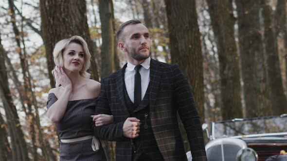 Proud Walk of Romantic Couple Looking Aside with Smile in Autumn Park