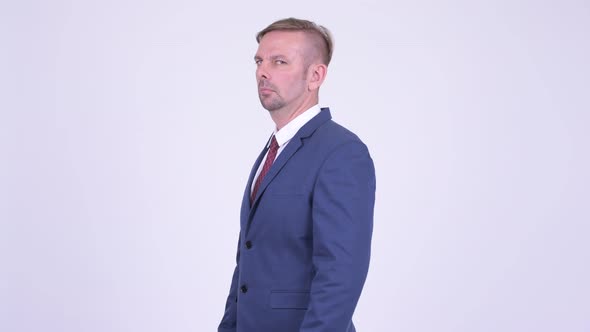 Profile View of Blonde Businessman Looking at Camera with Arms Crossed