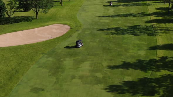 Passengers on Golf Cart Traveling Down Course During Summertime, Tracking Shot