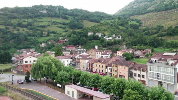 Cottages in a small village in a valley surrounded by green mountains by day in northern Spain.