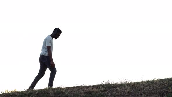 African American Man Walks on Hill Thinking Against Grey Sky