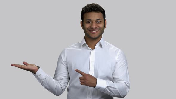 Happy Young Hindu Man Pointing at His Empty Palm for Copyspace