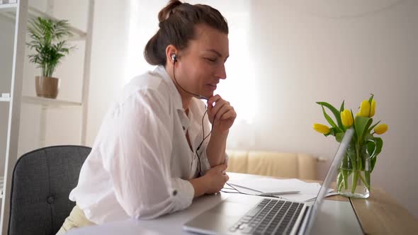 Happy Young Business Woman in a White Shirt Has a Video Call in the Office