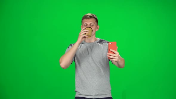 Young Man Walking Takes a Selfie with Smartphone and Drinking Coffee. Chroma Key. Slow Motion