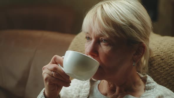 Aged Woman Drinking Tea on Sofa