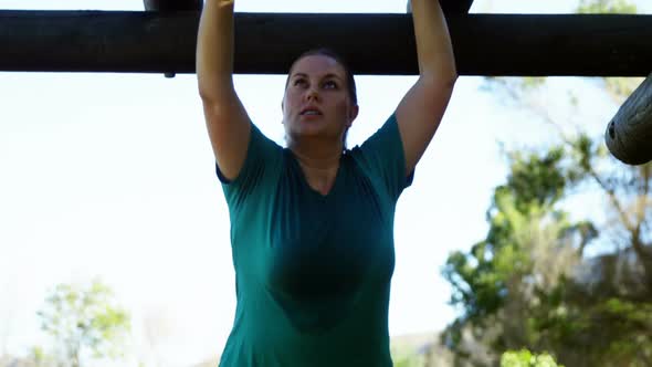 Determined woman exercising on monkey bar during obstacle course