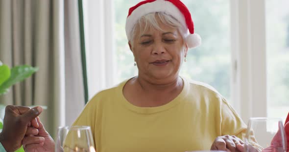 Happy diverse senior female and male friends celebrating meal at christmas time