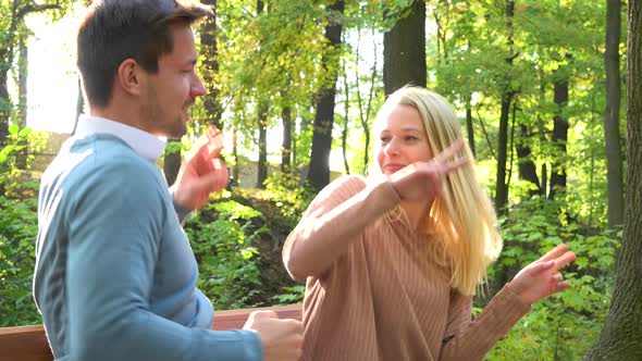 A Young Attractive Couple Dances on a Bench in a Park on a Sunny Day, Closeup