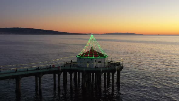 Manhattan Beach Pier Illuminated With Lights After Sunset In California - aerial pullback