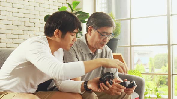 Asian father and son happily enjoy video games at home 