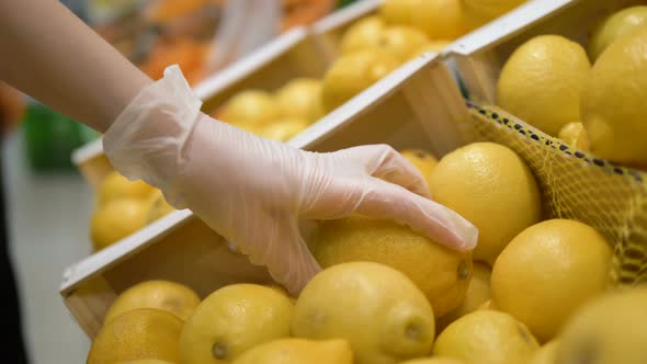 Girl in Medical Gloves Chooses Lemon in a Supermarket. Personal Protection Cocronovirus, Vitamin C