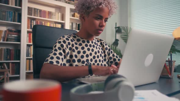 African American Woman Entrepreneur Typing on Laptop Keyboard Sits in Office