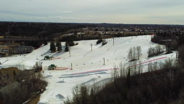 Aerial rise up above urban ski hill