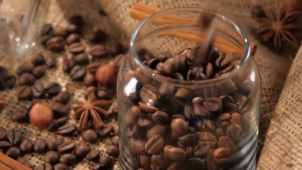 Pouring Coffee Beans Into a Bottle on Background with Hazelnut, Anise, Slow Motion