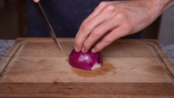 Close-up of cook cutting red onion in brunoise