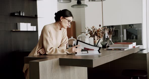 Serious Relaxed Woman Reading Book at Modern Home in Cozy Kitchen Interior