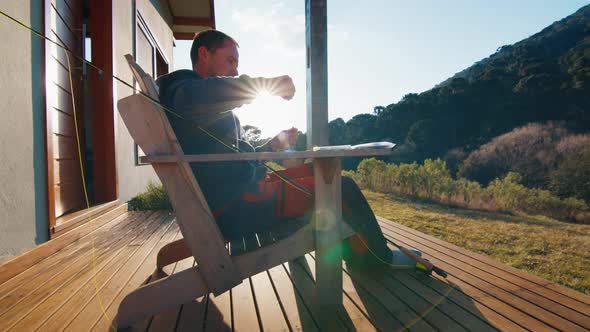 Fisherman Sits on the Chair and Checks His Fishing Gear in the Calm Home Terrace Environment