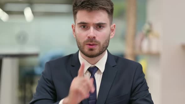 Young Businessman Putting Finger on Lips