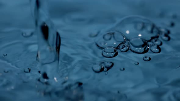 Macro Shot of Continuous Pouring of Liquid and Bubbles on the Surface