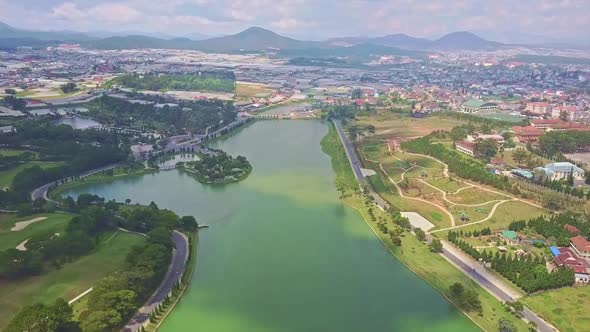 Flycam Moves Over Beautiful Quiet Lake Against Modern City