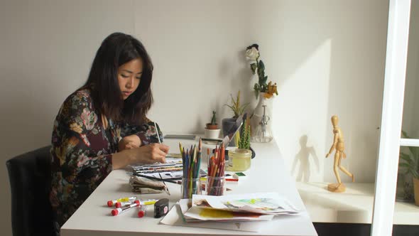Artist painting in her studio while using a digital tablet