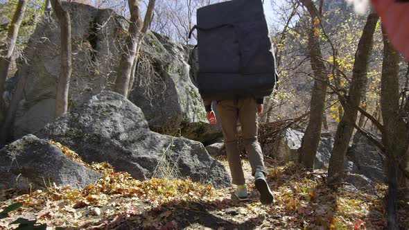 Young man and woman walking through forest with bouldering gear