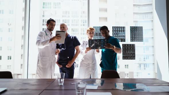 Group of Multi-ethnic Doctors Are Discussing History Disease of Patient Using MRI Scan and Tablet.