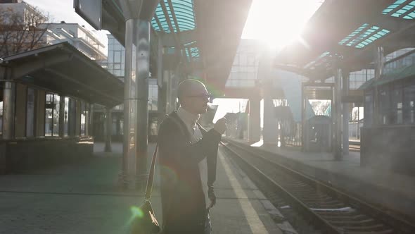 The Man is Nervous and Smoking on the Platform of the Railway Station Waiting for the Late Train