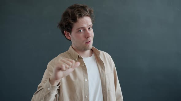 Slow Motion Portrait of Attractive Guy Pointing at Camera Then at Himself on Gray Background