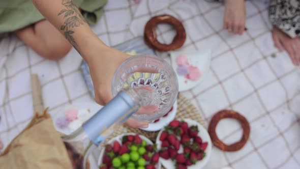 Pouring Wine Into the Glass and Put Cherries Inside at a Picnic