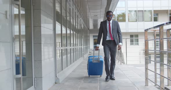 Handsome Afroamerican Businessman Carrying Suitcase While Walking Outside Business Center