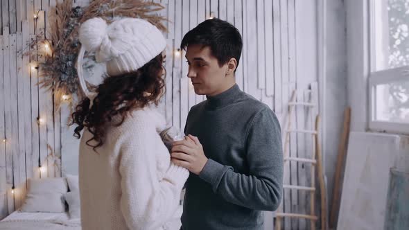 Young Man Dressed in a Gray Sweater, Gives His Girlfriend a Christmas Present