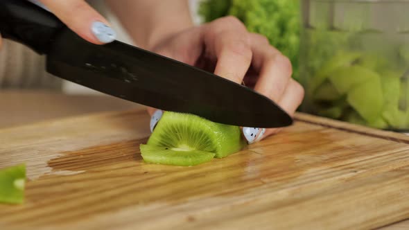 Slicing Kiwi Into Small Chunks with a Ceramic Knife on a Bamboo Cutting Board