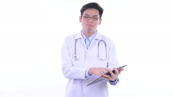 Happy Young Asian Man Doctor Talking While Reading on Clipboard