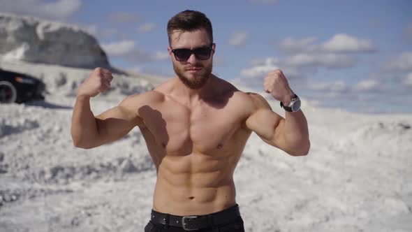 Athletic man shows his muscular body outdoors