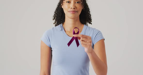 Video of smiling biracial woman holding black melanoma cancer ribbon