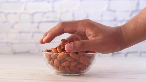 Hand Pick Almond Nut From a Bowl on Table