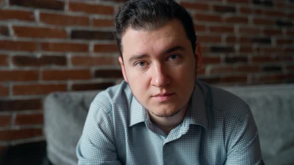 Portrait of authentic young adult man looking at camera indoors