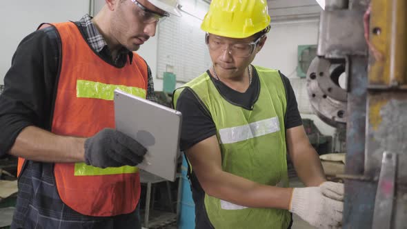 Caucasian and Asian engineer worker use tablet for maintenance checking machine