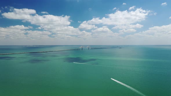 Distant View Of Sunshine Skyway Bridge Spanning Tampa Bay In Florida. Boats Sailing And Leaving Wake