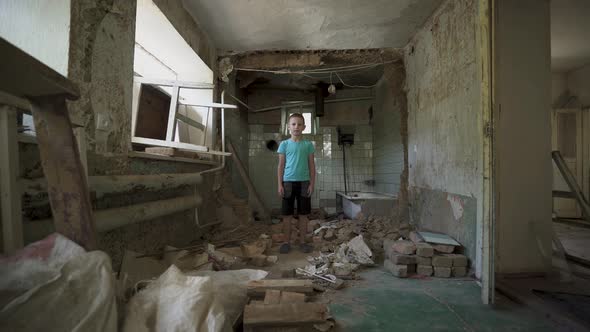 Ukrainian boy in a destroyed house. a homeless child in dirty clothes.