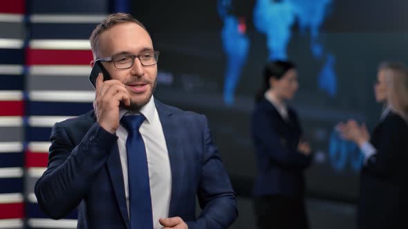 Handsome Smiling Male Entrepreneur Talk Use Smartphone Surrounded By Colleagues at Innovation Office