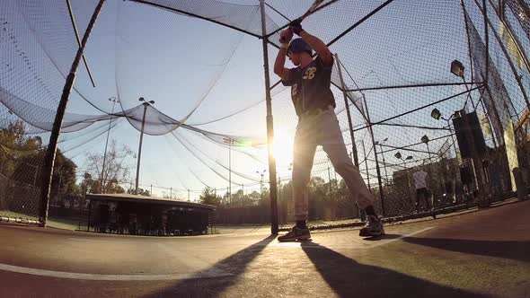 A baseball player practicing at the batting cages.