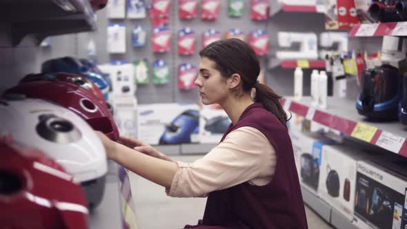 Girl Choosing New Vacuum Cleaner in Appliance Store