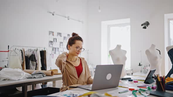 Young Female Fashion Designer Video Chatting with Client Showing Color Swatches to Laptop Working at